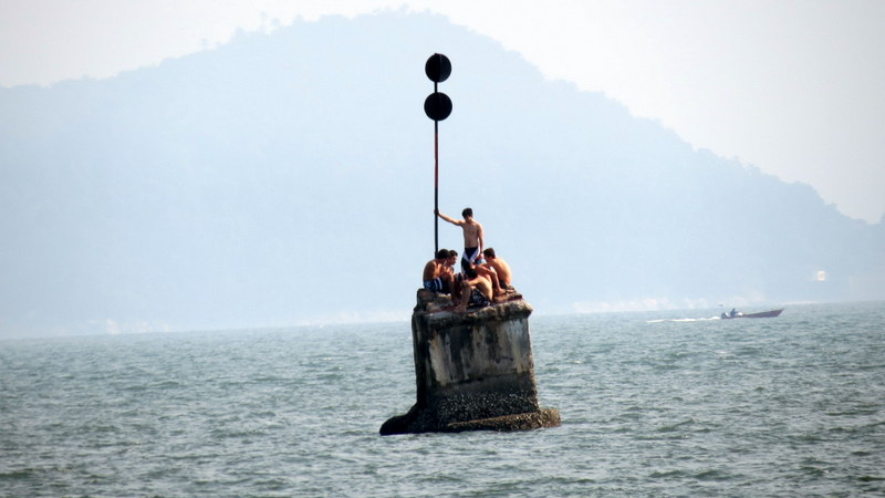 Jovens brincam no farol que foi quebrado pela for&ccedil;a do mar em Santos.